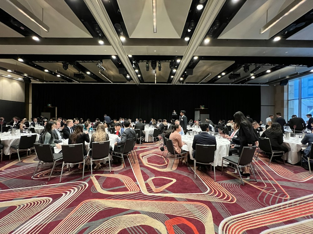 Attendees gathered around tables in a large meeting hall